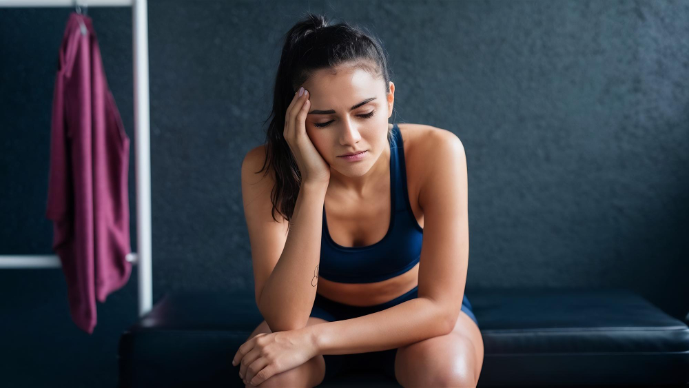 Mulher com fadiga muscular na academia